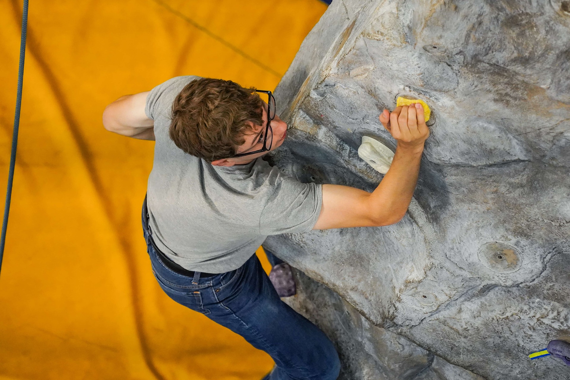 Student boulder climbing in the campus rec center on the rock wall